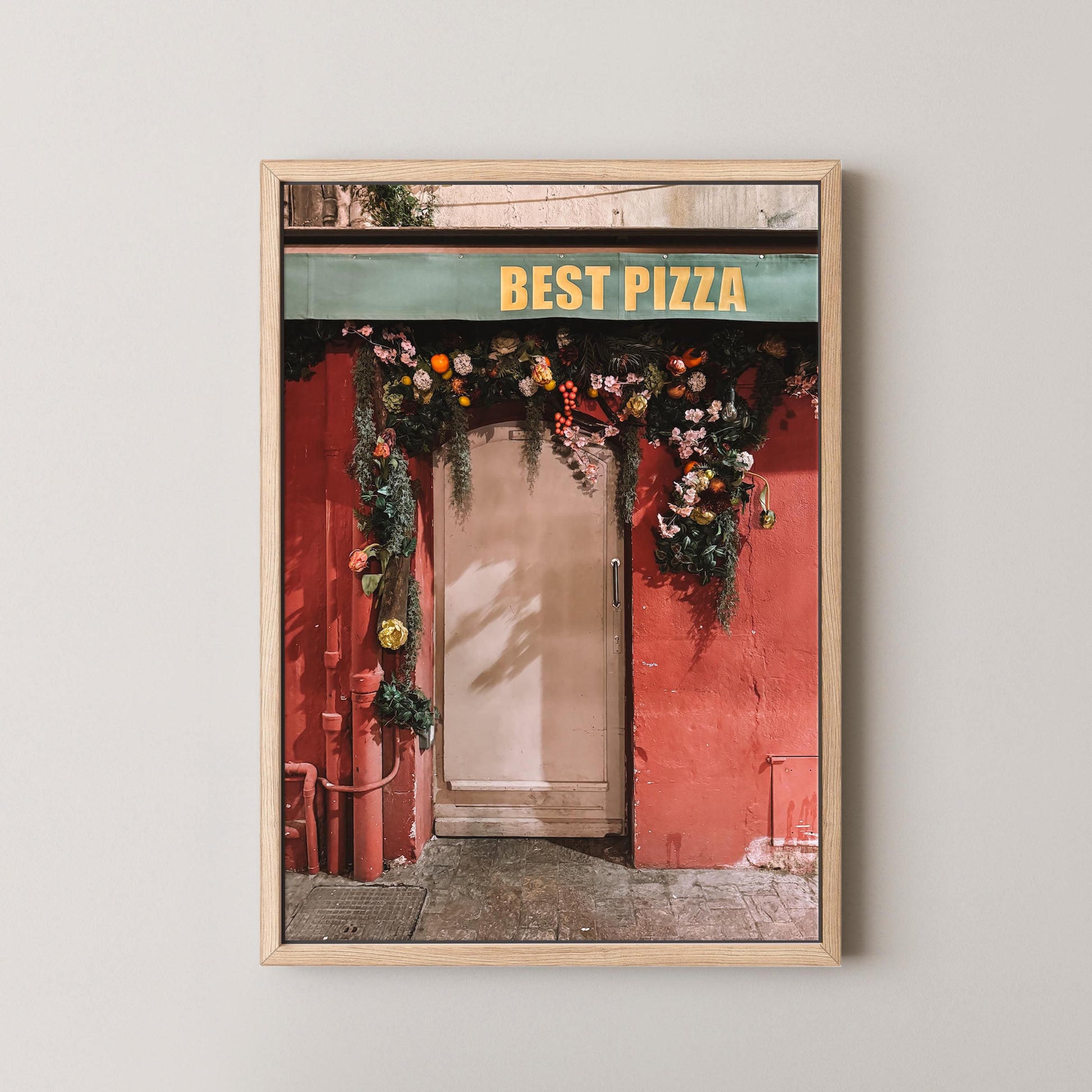 Framed photo of a pizza shop entrance with 'Best Pizza' sign and floral decorations.
