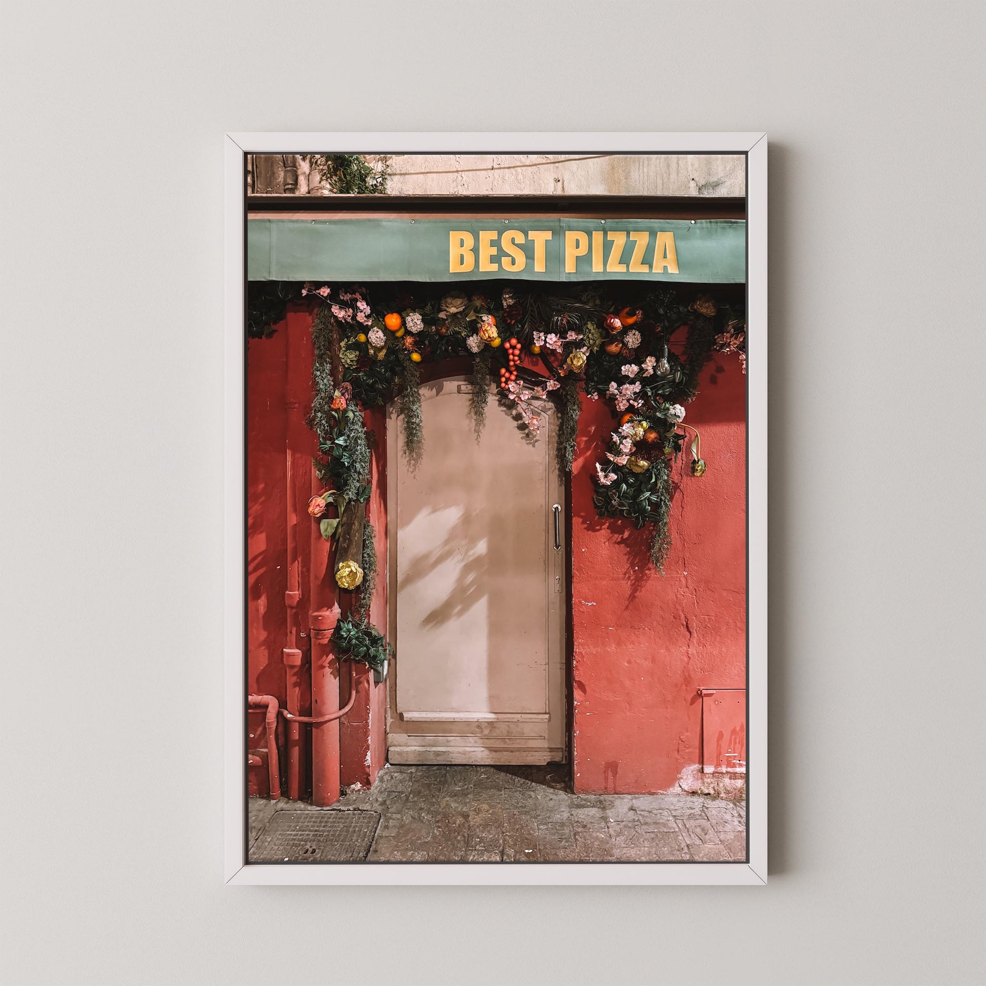 Framed photograph of a red building with 'Best Pizza' sign and floral decorations.