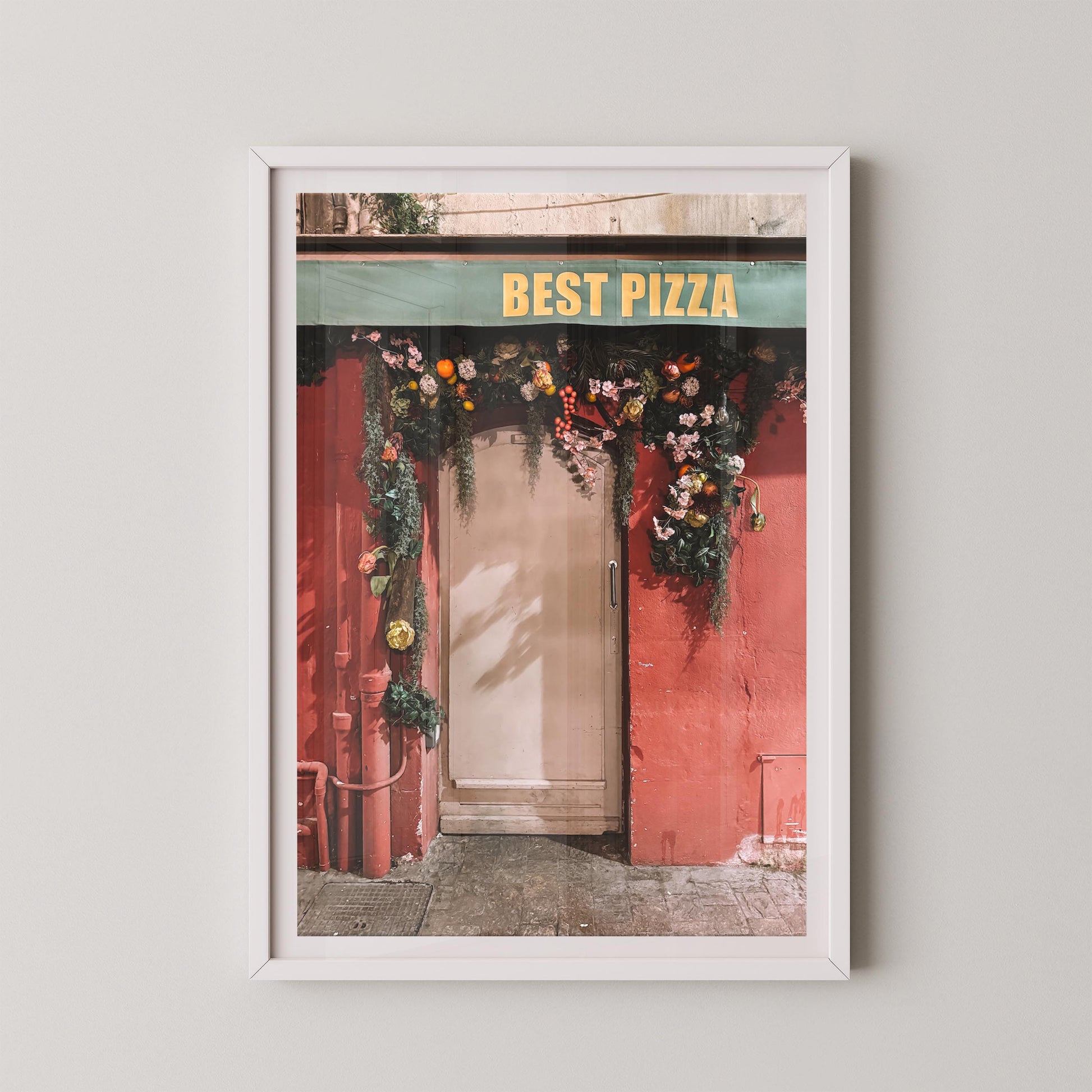 Framed print of a red door with floral decorations and 'Best Pizza' sign.