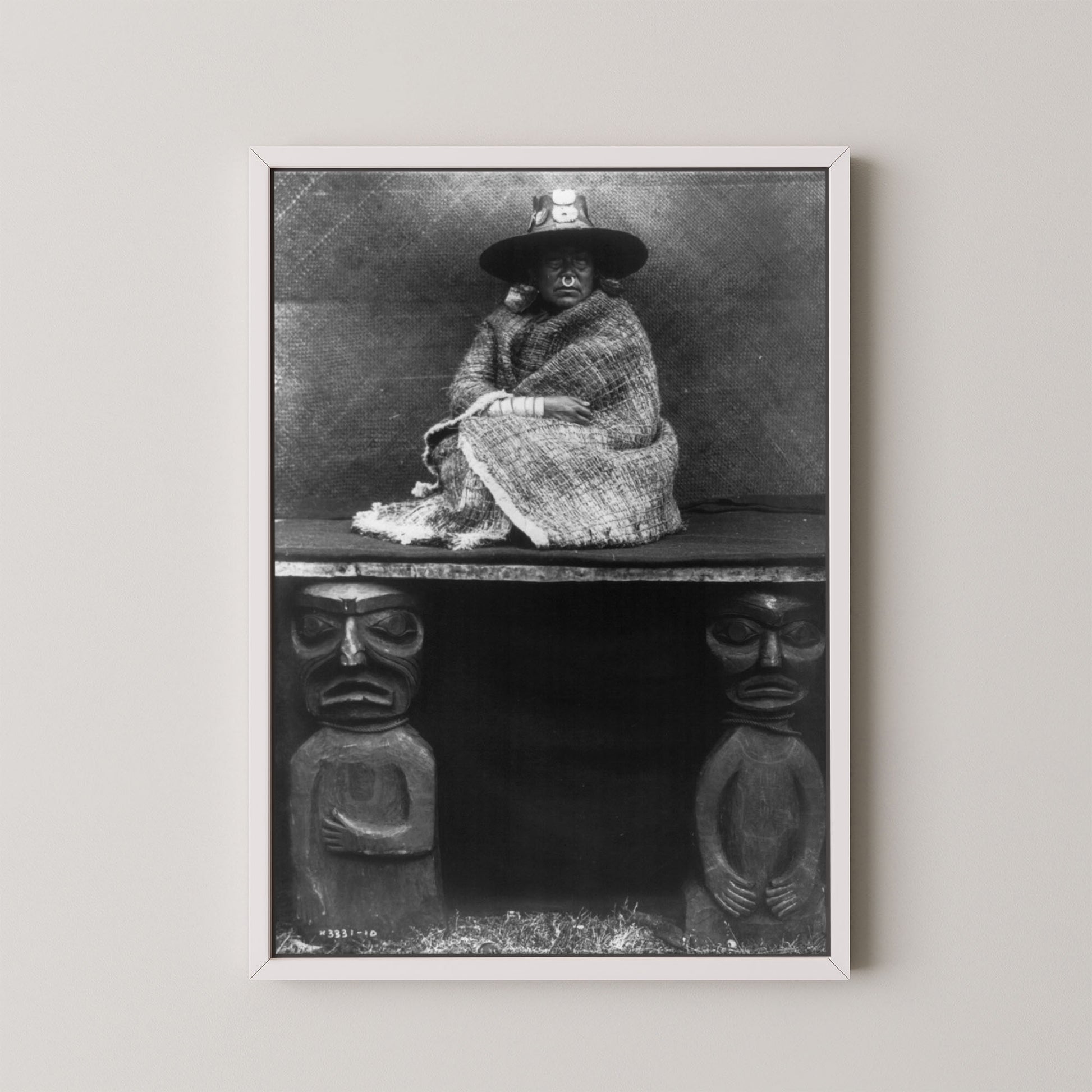 Framed black and white photograph of a person sitting on a bench with decorative carvings.