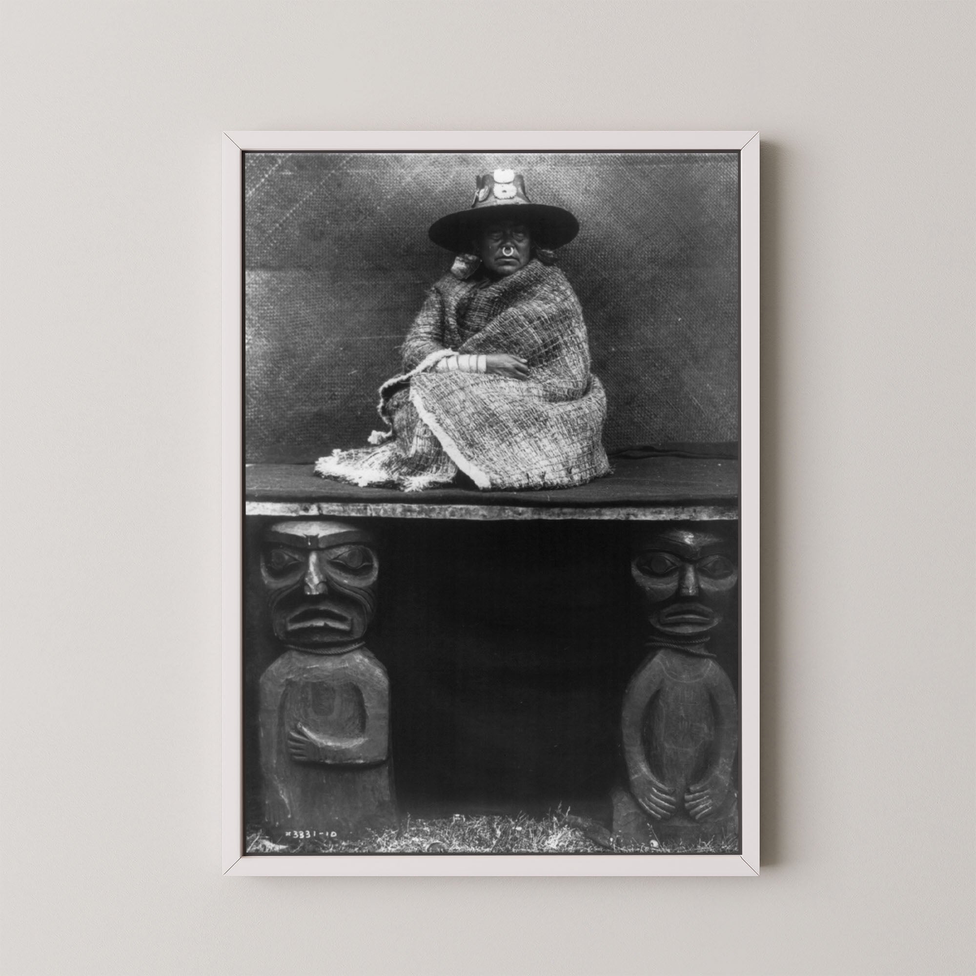 Framed black and white photograph of a person sitting on a bench with decorative carvings.