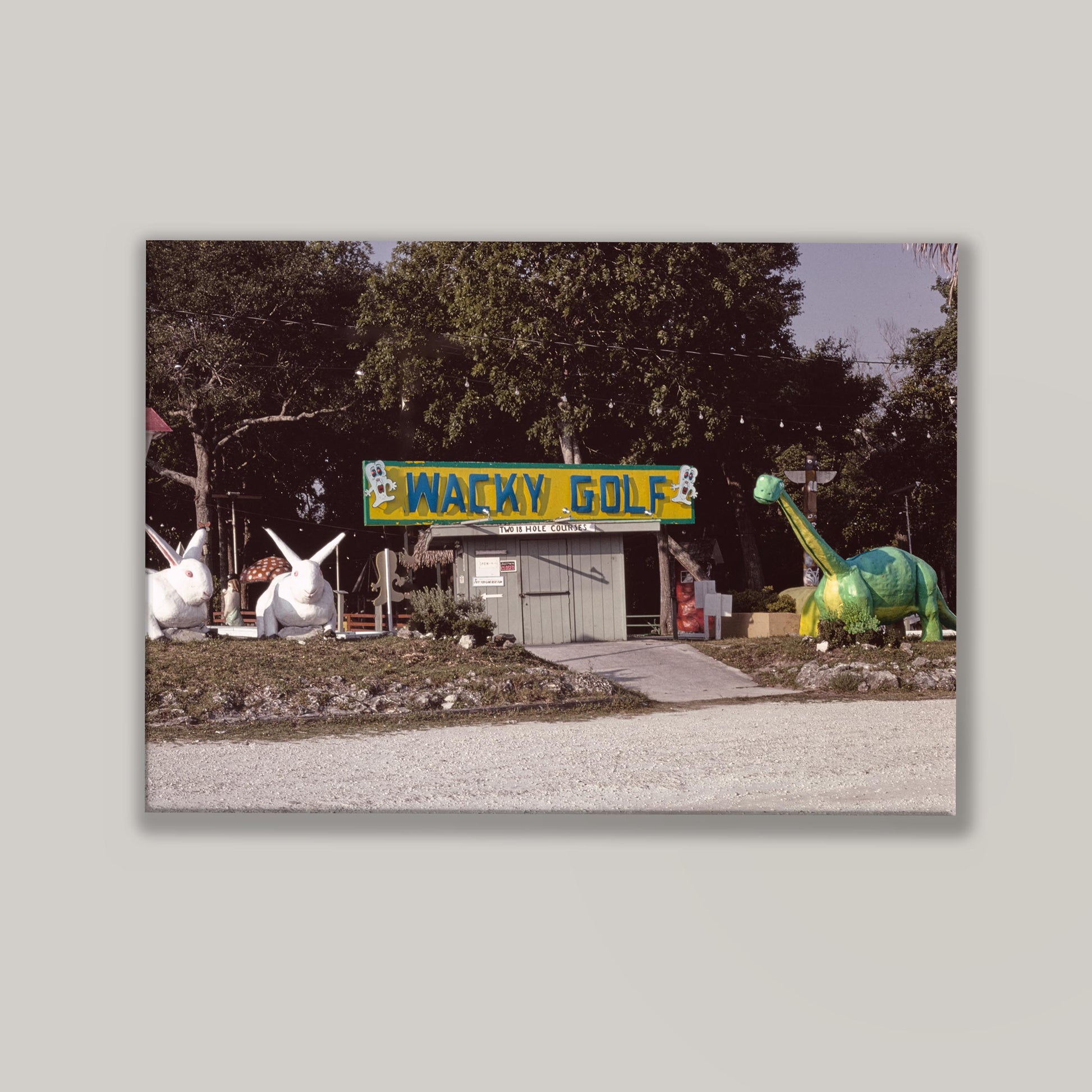 Entrance to Wacky Golf with cartoonish dinosaur and rabbit sculptures on a gray background