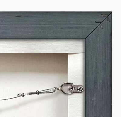 Close-up of a dark gray picture frame with a metal hook attached to it.